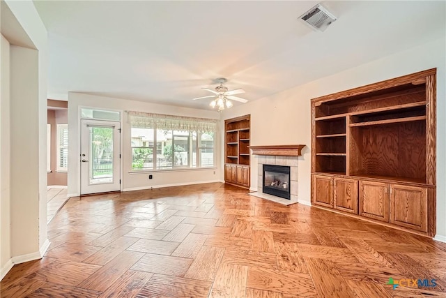 109 Ranch House Cv, Georgetown, TX 78633 - unfurnished living room featuring baseboards, a tiled fireplace, ceiling fan, and built in shelves
