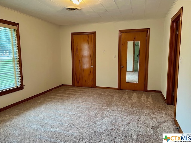 unfurnished bedroom featuring a closet, light colored carpet, and ornamental molding