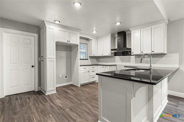 1935 Ross Ave, Waco, TX 76706 - kitchen with wall chimney exhaust hood, a sink, a peninsula, baseboards, and white cabinets
