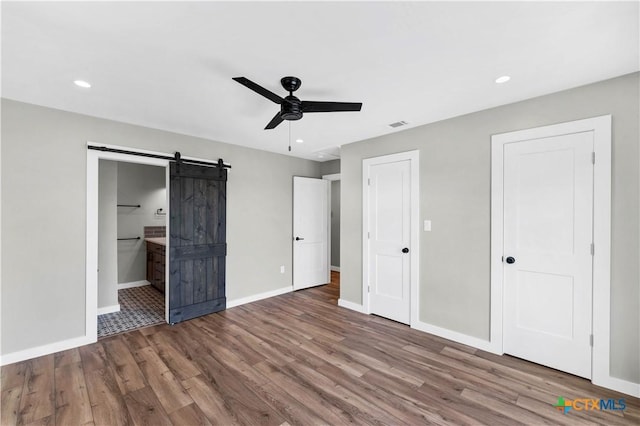 594 E S St, New Braunfels, TX 78130 - unfurnished bedroom with a barn door, wood finished floors, ensuite bath, ceiling fan, and recessed lighting