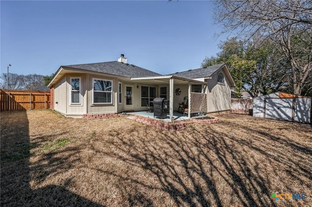 rear view of property featuring an outbuilding, a fenced backyard, a patio, and a storage unit