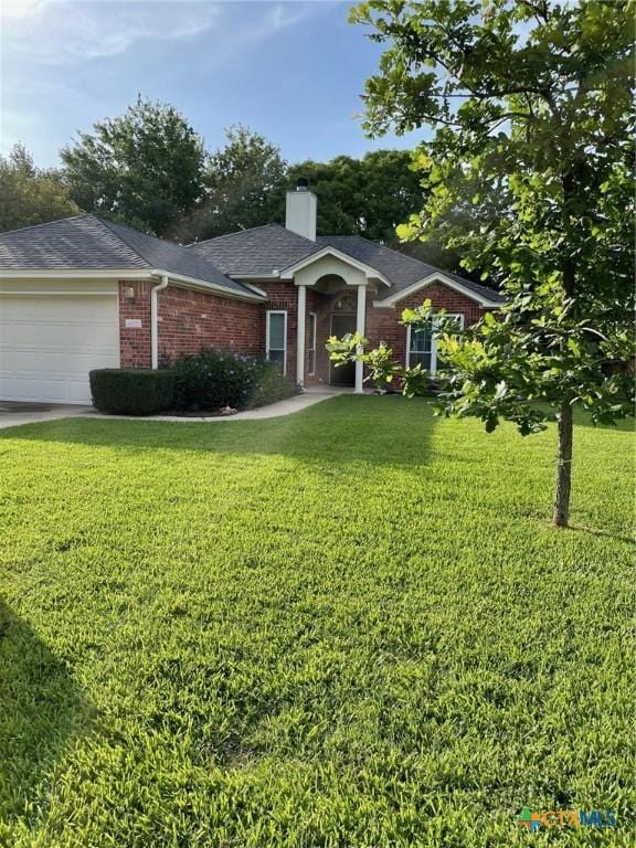 4605 Danbury Dr, Temple, TX 76502 - single story home featuring a front yard, a chimney, a garage, brick siding, and driveway