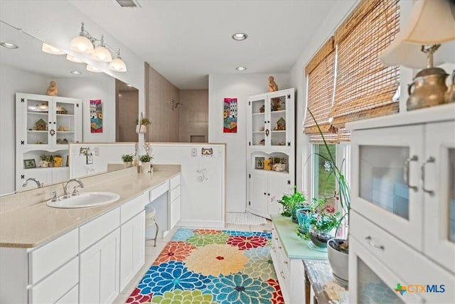 bathroom featuring recessed lighting, vanity, baseboards, and a shower