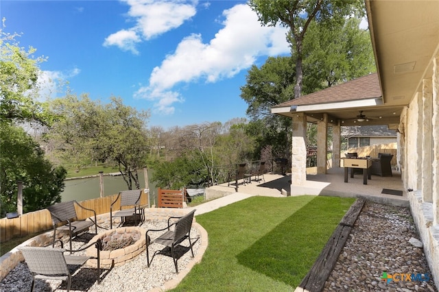 view of yard with ceiling fan, a water view, an outdoor living space with a fire pit, and a patio