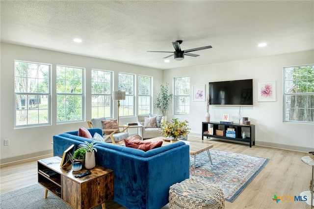 living room featuring a textured ceiling, light hardwood / wood-style floors, and ceiling fan