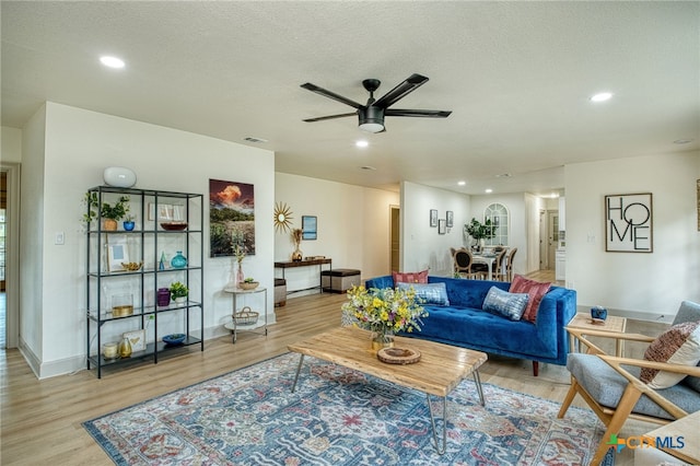 living room featuring a textured ceiling, ceiling fan, and light hardwood / wood-style flooring