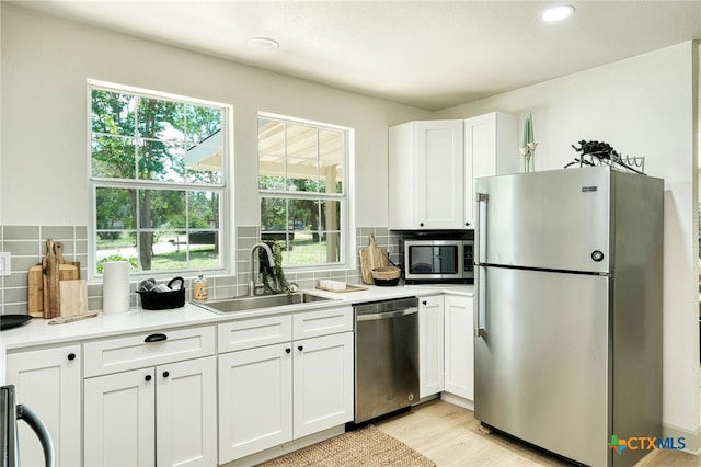 kitchen with stainless steel appliances, white cabinets, sink, and decorative backsplash