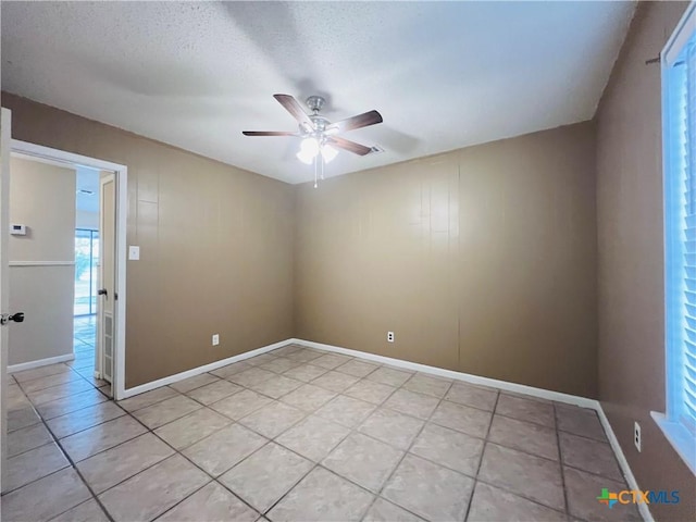 empty room featuring a textured ceiling, ceiling fan, and light tile patterned flooring