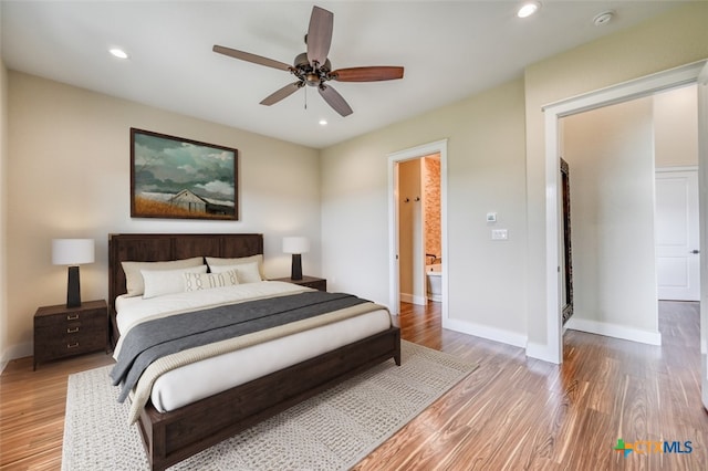 bedroom featuring hardwood / wood-style flooring, ceiling fan, and ensuite bath