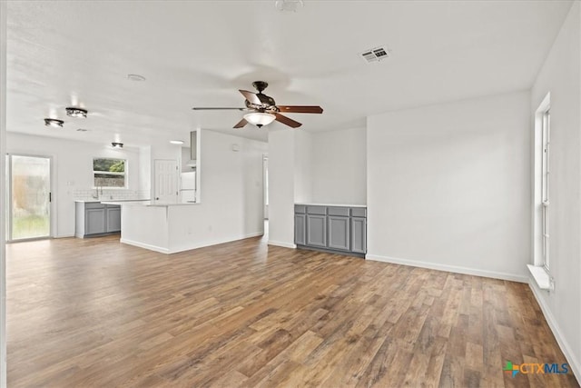 unfurnished living room with hardwood / wood-style flooring and ceiling fan