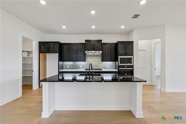 1516 Dancing Oak Ln, San Marcos, TX 78666 - kitchen featuring wall oven, stainless steel microwave, backsplash, light wood finished floors, and recessed lighting