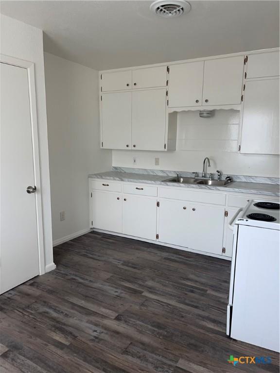 kitchen with a sink, visible vents, white cabinets, electric range, and dark wood-style flooring