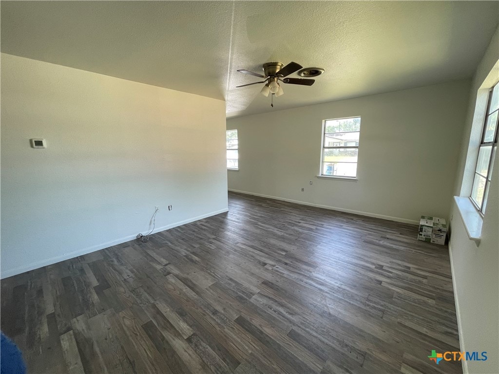 empty room with a textured ceiling, dark hardwood / wood-style floors, and ceiling fan