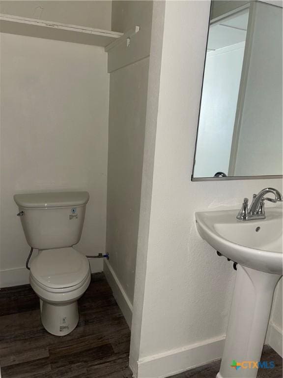 bathroom featuring toilet, wood finished floors, and baseboards