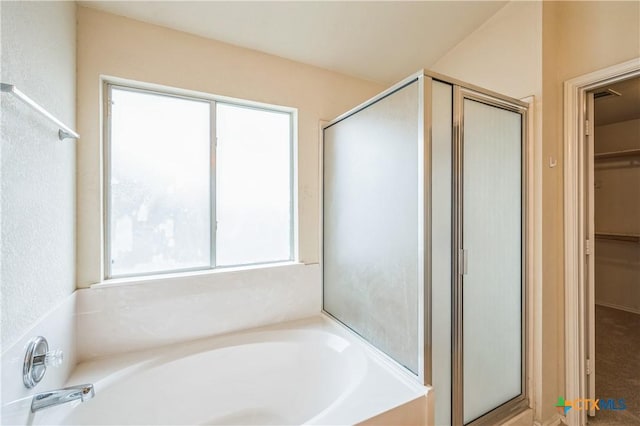 bathroom featuring a stall shower, a garden tub, and a spacious closet