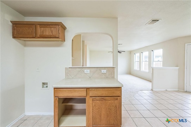 kitchen with light countertops, a ceiling fan, light tile patterned floors, backsplash, and visible vents