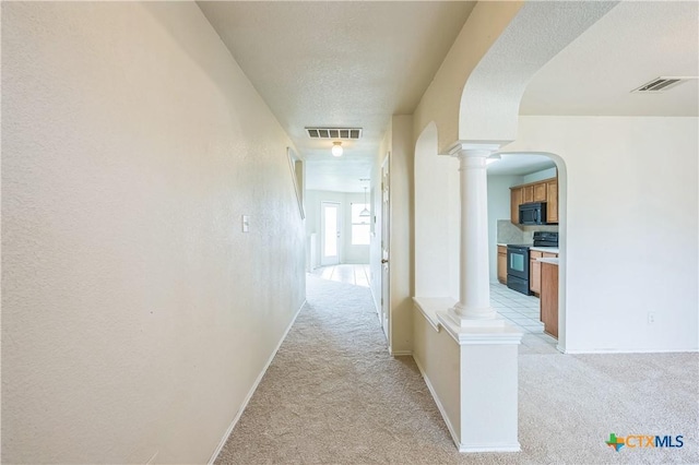 hall with arched walkways, decorative columns, light carpet, and visible vents