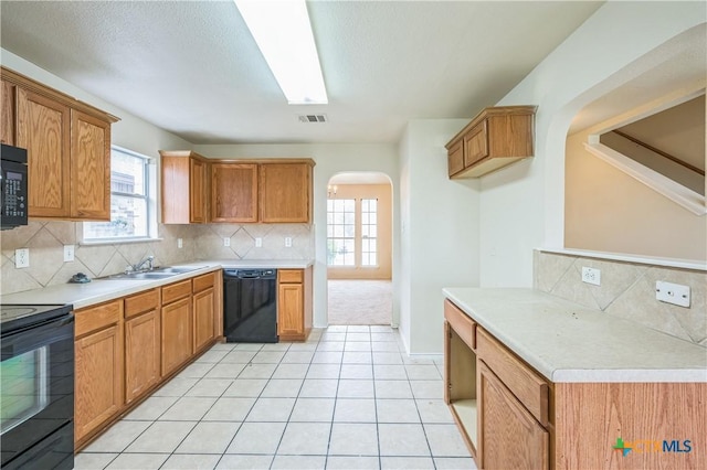 kitchen with visible vents, a sink, tasteful backsplash, arched walkways, and black appliances