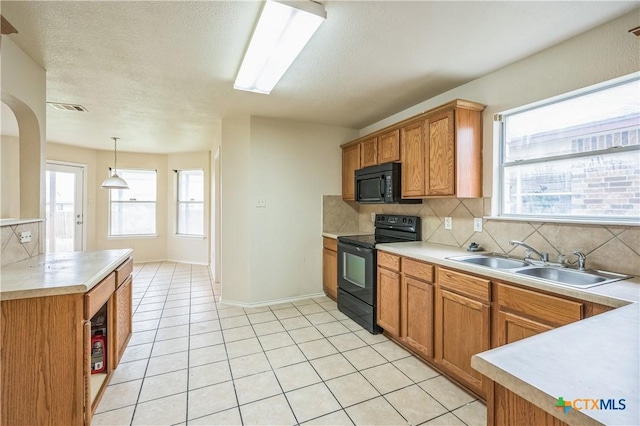kitchen featuring light countertops, decorative backsplash, a sink, and black appliances