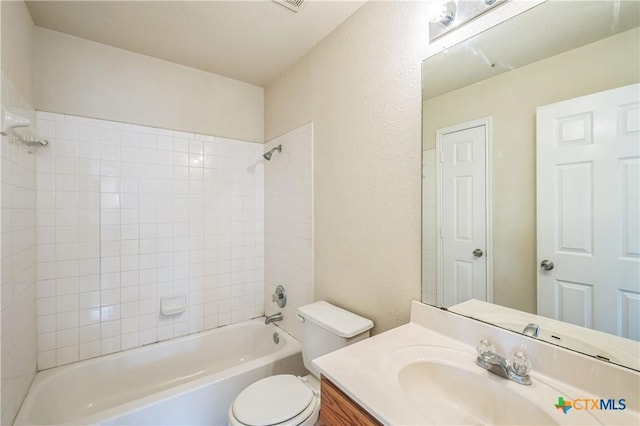 bathroom featuring toilet, a textured wall, shower / washtub combination, and vanity