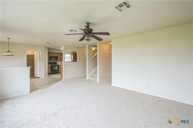 unfurnished living room with ceiling fan, visible vents, light carpet, and stairway
