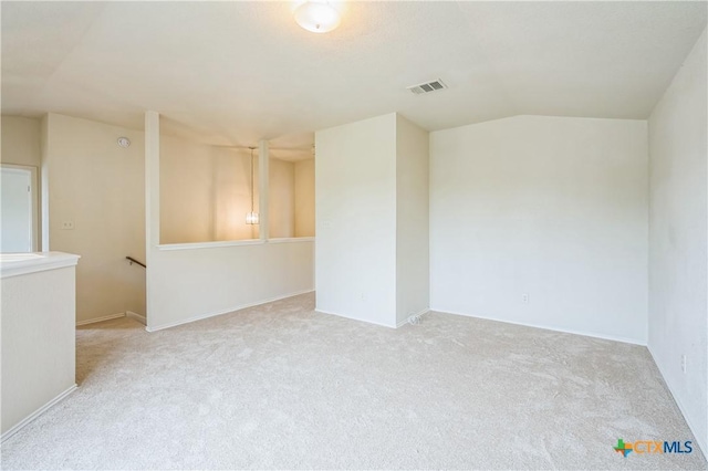 spare room featuring visible vents, carpet, and lofted ceiling