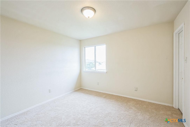 unfurnished room featuring baseboards and light carpet