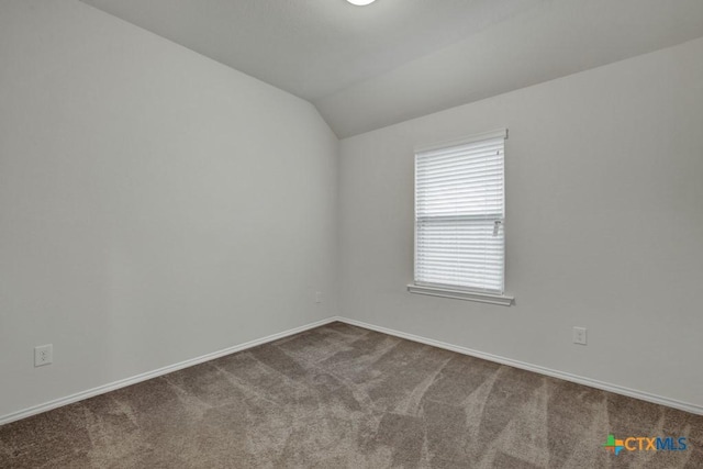 carpeted spare room featuring vaulted ceiling