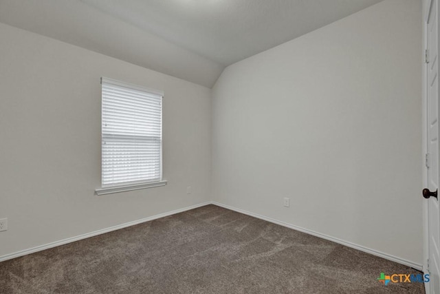 carpeted spare room with vaulted ceiling