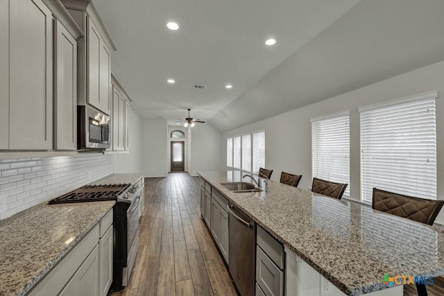 kitchen with a breakfast bar, wood-type flooring, sink, backsplash, and stainless steel appliances