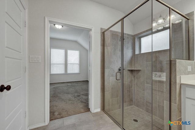 bathroom with tile patterned floors, vanity, a shower with shower door, and lofted ceiling