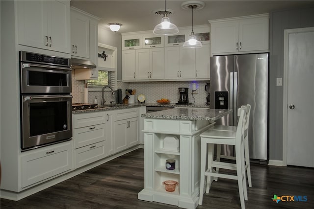 kitchen featuring stainless steel appliances, hanging light fixtures, sink, white cabinets, and a center island