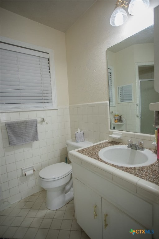 bathroom featuring tile walls, tile patterned floors, vanity, toilet, and a shower with shower door