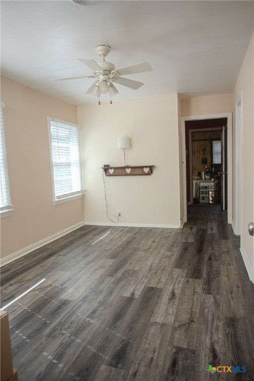 unfurnished living room featuring dark wood-type flooring and ceiling fan