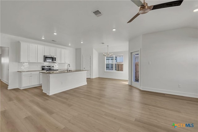 kitchen featuring appliances with stainless steel finishes, white cabinetry, backsplash, light hardwood / wood-style floors, and an island with sink