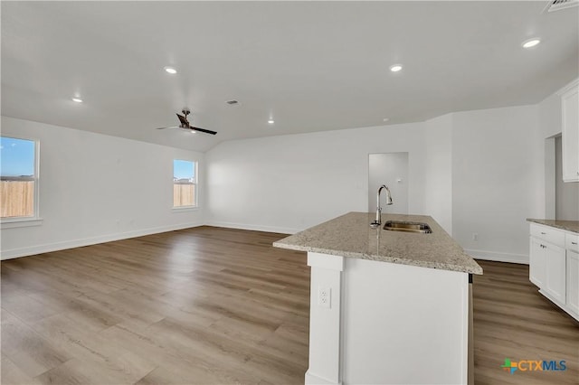 kitchen with white cabinetry, sink, a center island with sink, and light stone counters