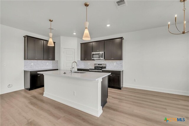 kitchen with white cabinetry, sink, a center island with sink, and light stone counters