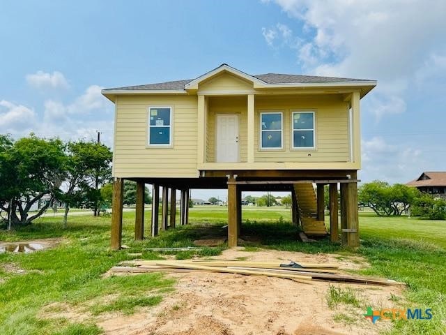 view of front facade with dirt driveway, a carport, and a front lawn