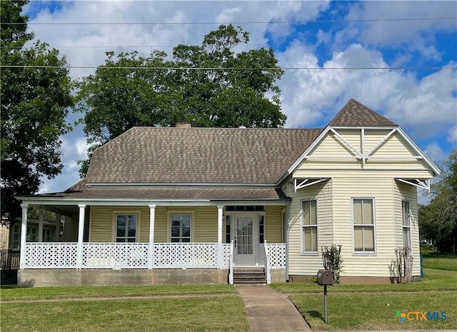 114 N Market St, Goliad, TX 77963 - view of front of home with a porch, roof with shingles, a front lawn, and a chimney