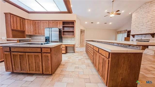 kitchen with open shelves, decorative backsplash, a kitchen island, stainless steel refrigerator with ice dispenser, and a ceiling fan