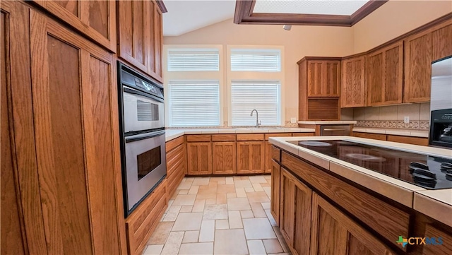 kitchen with light countertops, stainless steel appliances, brown cabinets, and backsplash