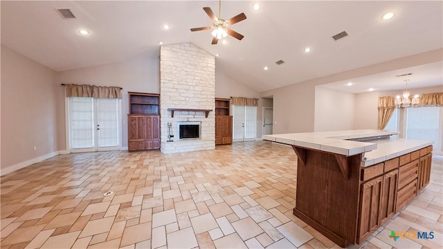 kitchen with tile countertops, baseboards, visible vents, and ceiling fan with notable chandelier
