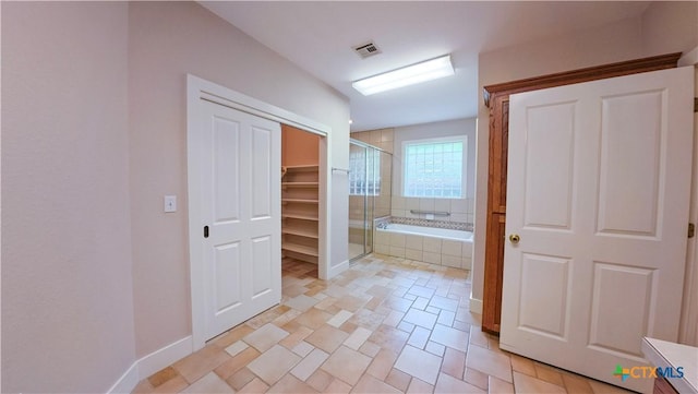 bathroom with a closet, visible vents, a garden tub, and a stall shower