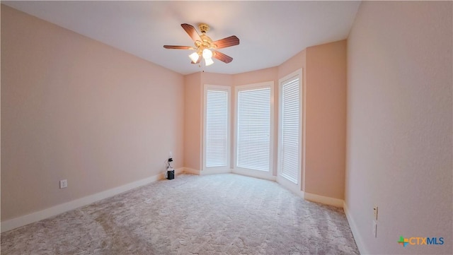 carpeted spare room with ceiling fan and baseboards