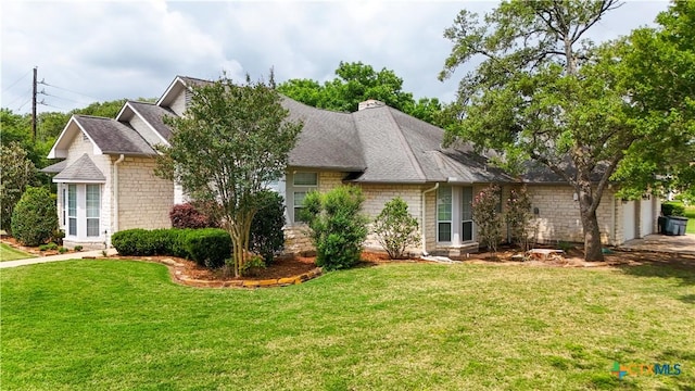 view of front of house featuring a shingled roof, an attached garage, and a front yard