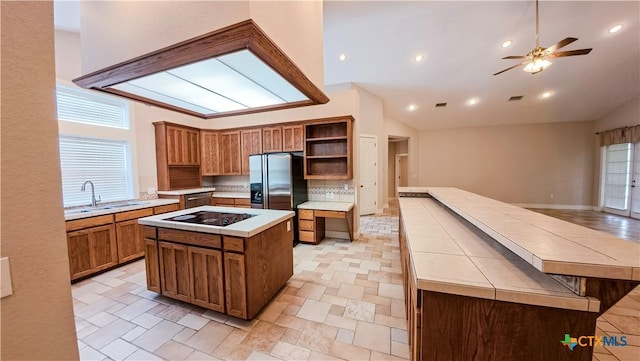 kitchen featuring a kitchen island, open shelves, black electric stovetop, lofted ceiling, and stainless steel fridge