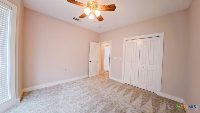 unfurnished bedroom with carpet flooring, a ceiling fan, baseboards, visible vents, and a closet