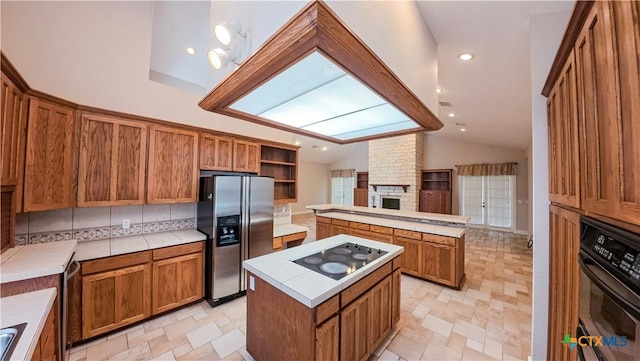 kitchen featuring brown cabinets, a center island, a peninsula, lofted ceiling, and black appliances