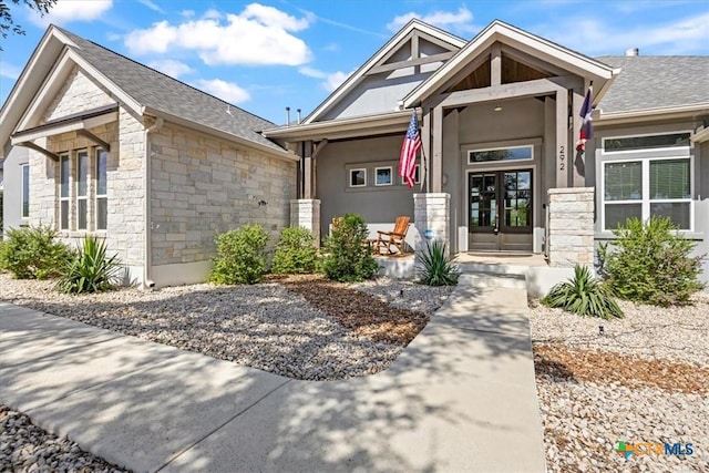 292 Scenic Cyn, New Braunfels, TX 78132 - view of front of property featuring stone siding, a porch, a shingled roof, and french doors