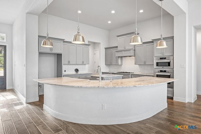292 Scenic Cyn, New Braunfels, TX 78132 - kitchen with gray cabinets, a large island with sink, dark wood-style flooring, gas cooktop, and light stone counters